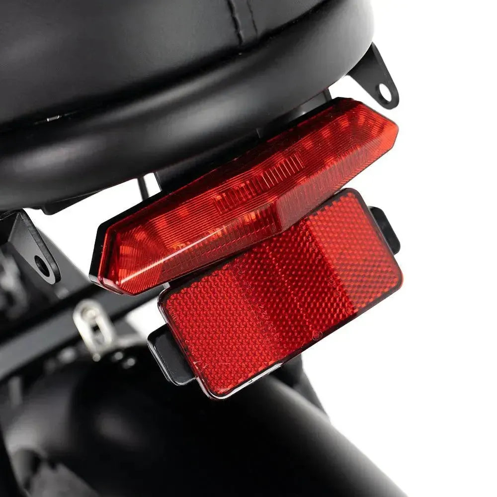 Ouxi V8 2025 Fatbike in Schwarz, Detail des roten Rücklichts mit Reflektor unter dem Sattel
