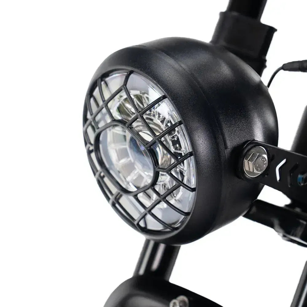 Ouxi V8 2025 Fatbike in Schwarz, Detail des runden LED-Scheinwerfers mit schwarzem Schutzgitter